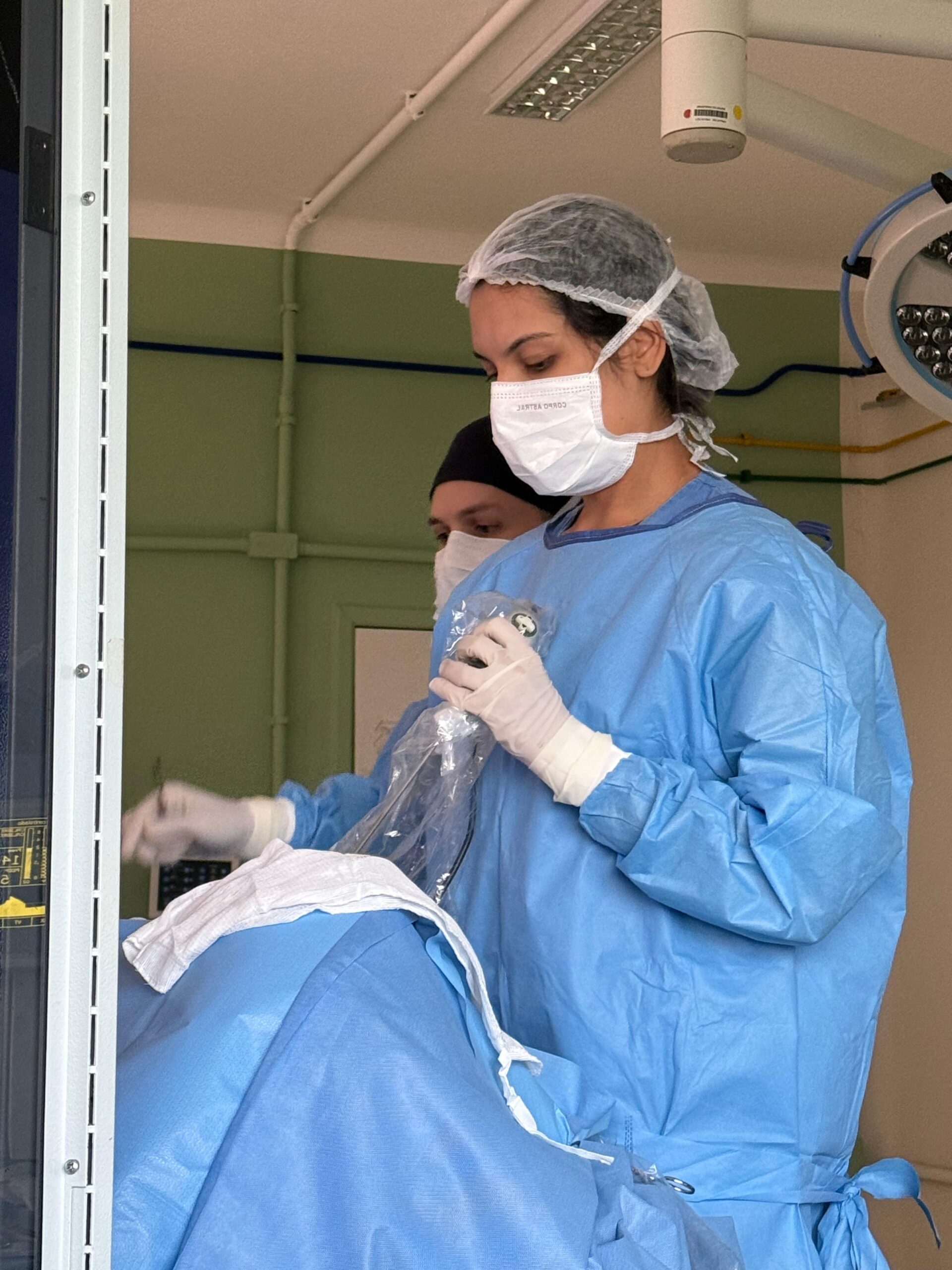 Profissional de saúde usando roupas cirúrgicas em um ambiente clínico, preparando-se para um procedimento.