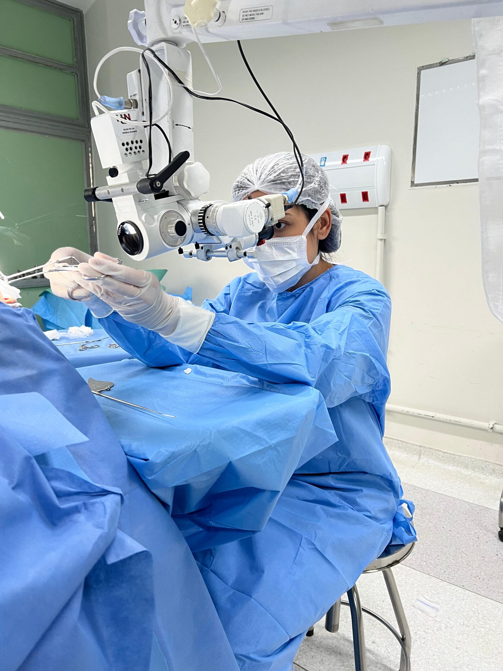Cirurgião otorrinolaringologista realizando um procedimento médico com equipamento cirúrgico em um ambiente estéril.